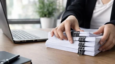 Businesswoman organizing stack of documents with binder clips at office desk Stock Footage 346476338