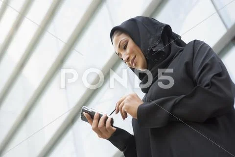 Businesswoman outdoors by building using personal digital assistant and smiling Stock Photos