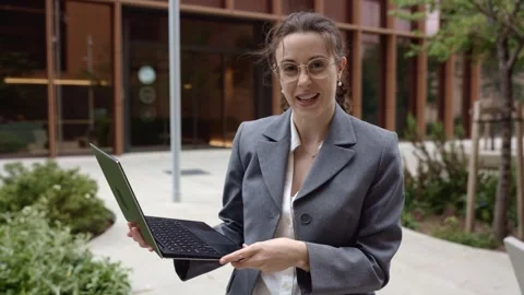 Businesswoman presenting and talking while holding a laptop outdoors Video stock 342288337