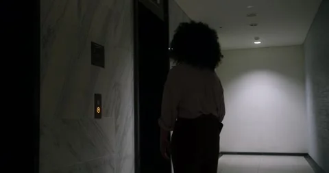 A businesswoman presses the elevator call button and waits for the elevator. A Stock-Footage 288043289