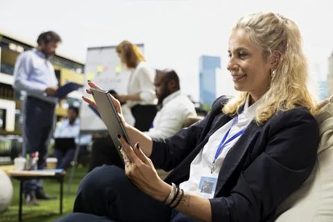 Businesswoman reading data from tablet while seated at outdoor workspace Stock Photos