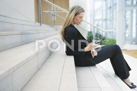 Businesswoman Reading Text Message On Office Steps Stock Photos