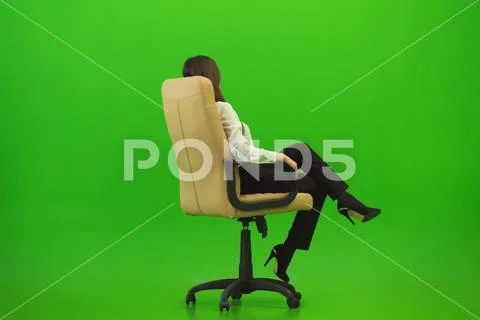The businesswoman sitting on the chair on the green background Stock Photos