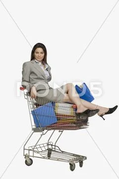 Businesswoman sitting in a shopping cart with files Stock Photos