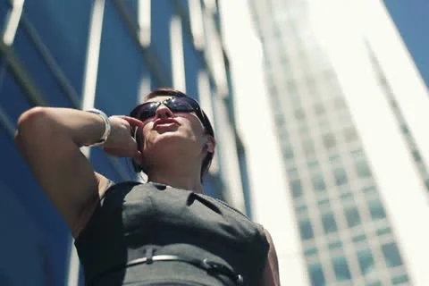 Businesswoman by the skyscrapers talking on cellphone NTSC Stock Footage