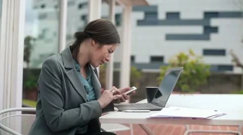 Businesswoman with smartphone and laptop outdoors HD Stock Footage