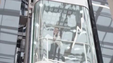 Businesswoman with a smartphone going down in an elevator with a glass wall. Stock Footage 224220907