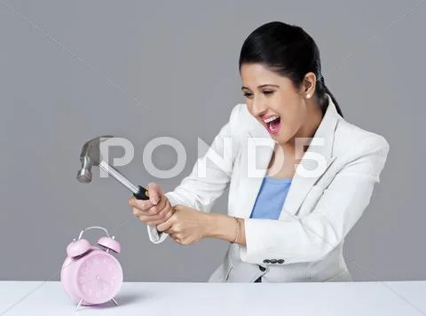 Businesswoman smashing alarm clock with hammer Stock Photos