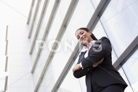 Businesswoman standing outdoors by building smiling (high key/selective focus) Stock Photos