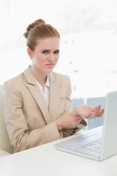 Businesswoman suffering from wrist pain in office Stock Photos