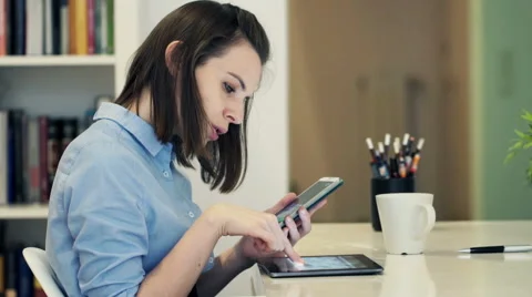 Businesswoman with tablet computer calculating data on smartphone by table  HD Stock Footage 49729797