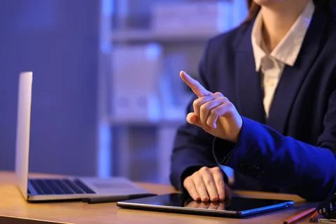 Businesswoman with tablet computer using virtual screen in office at night, c Stock Photos