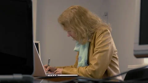 Businesswoman taking notes while using laptop Stock Footage 169520463