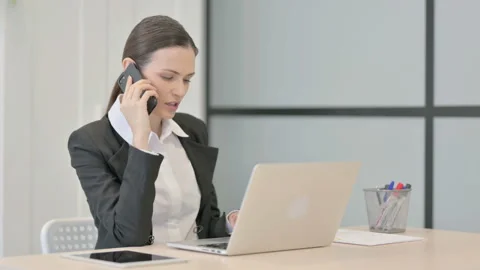 Businesswoman Talking on Phone while using Laptop Stock Footage 233379527