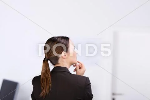 Businesswoman thinking with hand on chin in office Stock Photos