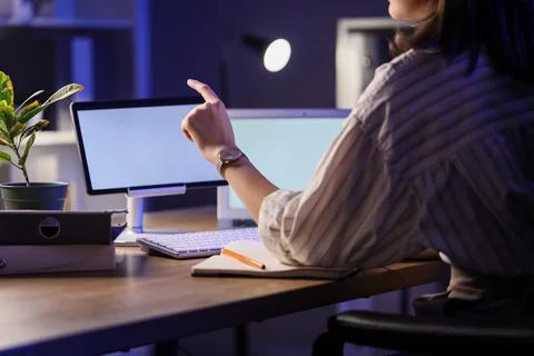 Businesswoman using blank tablet computer in office at night, back view. Cust Stock Photos