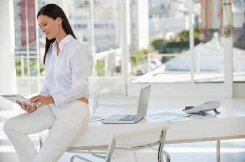 Businesswoman using a digital tablet while sitting on a table in an office Stock Photos