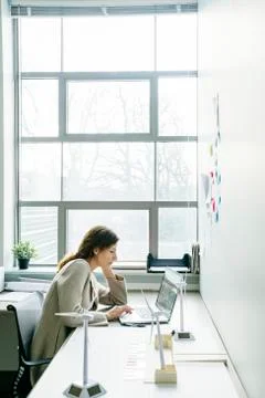 Businesswoman using laptop computer while sitting at desk in office Stock Photos