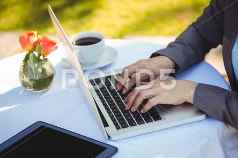 Businesswoman Using Laptop In Patio Of Restaurant