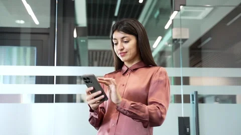 Businesswoman using smartphone while standing in modern glass business office.  Видео 332849340