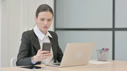 Businesswoman using Smartphone while using Laptop Video stock 233379340