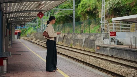 Businesswoman using a smartphone while waiting for a train on a station Stock Footage 338343416