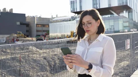Businesswoman using smartphone while walking near construction area Stock Footage 244246529