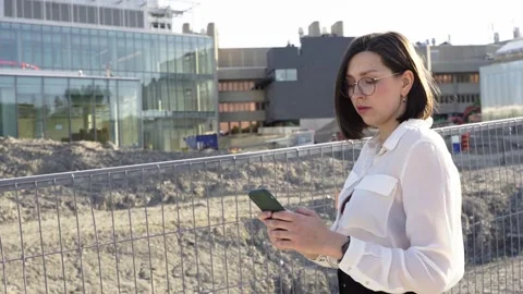 Businesswoman using smartphone while walking near construction area Stock Footage 244246538