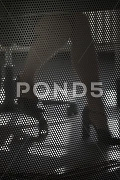 A businesswoman working at a desk, close-up of legs behind wire mesh screen Stock Photos