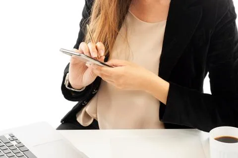 A businesswoman working at the desk holding a smartphone in the hands Stock Photos