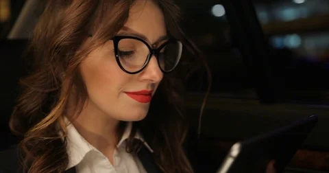 Businesswomen scrolling using tablet in car with city at night light background Stock Footage