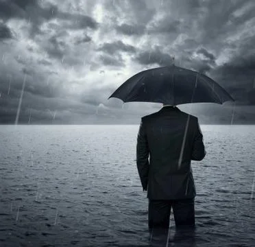 Businnessman standing in the dramatic ocean befre storm Stock Photos