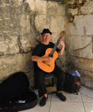 Busker playing classical guitar by historic gate. Stock Photos