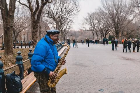 Busker playing saxophone while other passersby pass around him, Central Par.. Stock Photos