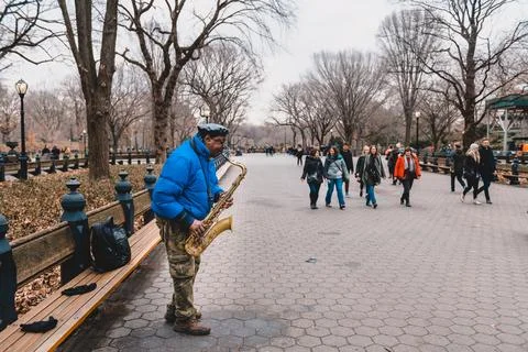 Busker playing saxophone while other passersby pass around him, Central Par.. Stock Photos