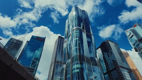 A bustling cityscape from low-angle, featuring a central cylindrical skyscraper Stock Footage 338311547