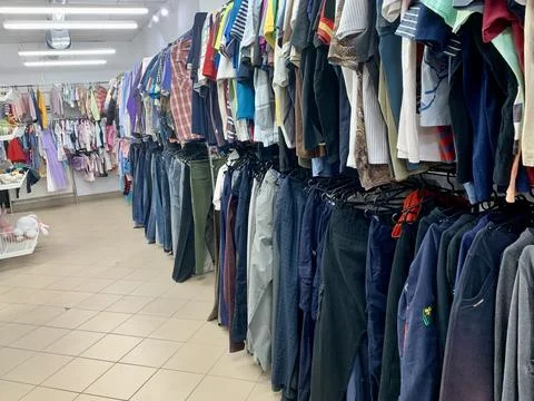 A bustling clothing store features rows of neatly organized clothes on racks. Stock Photos