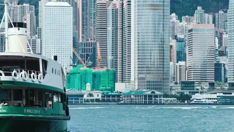 A bustling harbor in Hong Kong with a large green and white ferry moving slowly Video stock 338310976