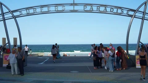 A bustling scene of beach life, featuring the iconic Surfers Paradise archway Stock Footage 325499326