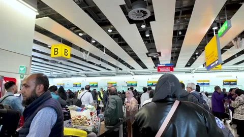 A busy airport check in queue shows numerous passengers with luggage waiting in Stock Footage 334973360