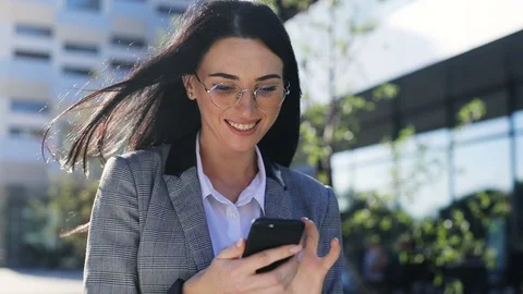 Busy beautiful businesswoman working smiling and using smartphone outside sunny Stock Footage