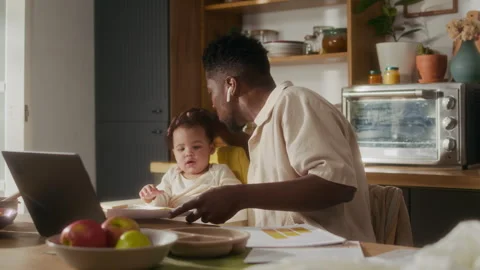 Busy Black Dad Working Remotely using Computer at Kitchen Table Stock Footage 315914548