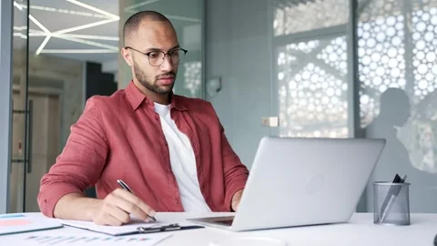 Busy businessman doing paperwork using laptop sitting at desk at workplace  Stock Footage 311622175