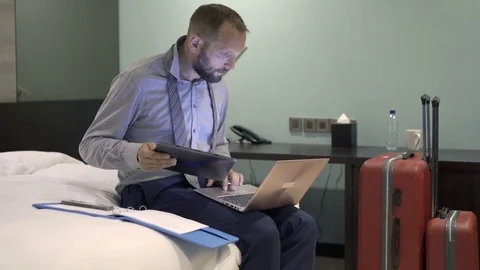 Busy businessman working with tablet, laptop, smartphone and documents in hotel Stock Footage