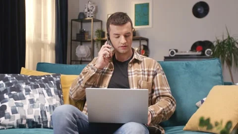 Busy Caucasian worker sitting on soft couch while working on laptop. Actively Stock Footage 245431926