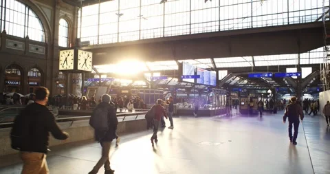 Busy commuters walking through backlit Main Station atrium at sunset, real time Stock Footage 330937491