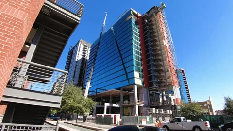 A busy construction site of a crane, elevator, workers, and traffic Video stock 141903511