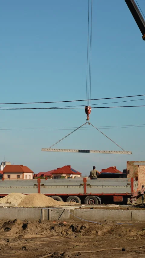 A busy construction site featuring a crane lifting a concrete slab from a Video stock 297312295