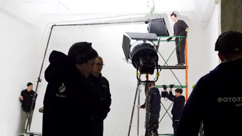Busy crew sets up lights and heavy gear in spacious studio Stock Footage 308950349