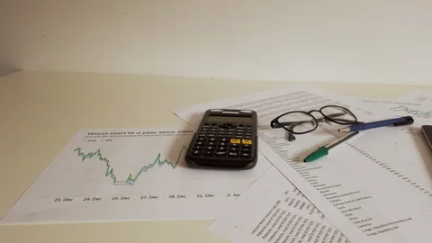 Busy desktop with office material, a tablet pad with graphs and statistics of Stock Footage 119477705